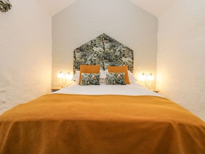 Relax in a serene bedroom with a high ceiling, ornate headboard, and plush bedding.