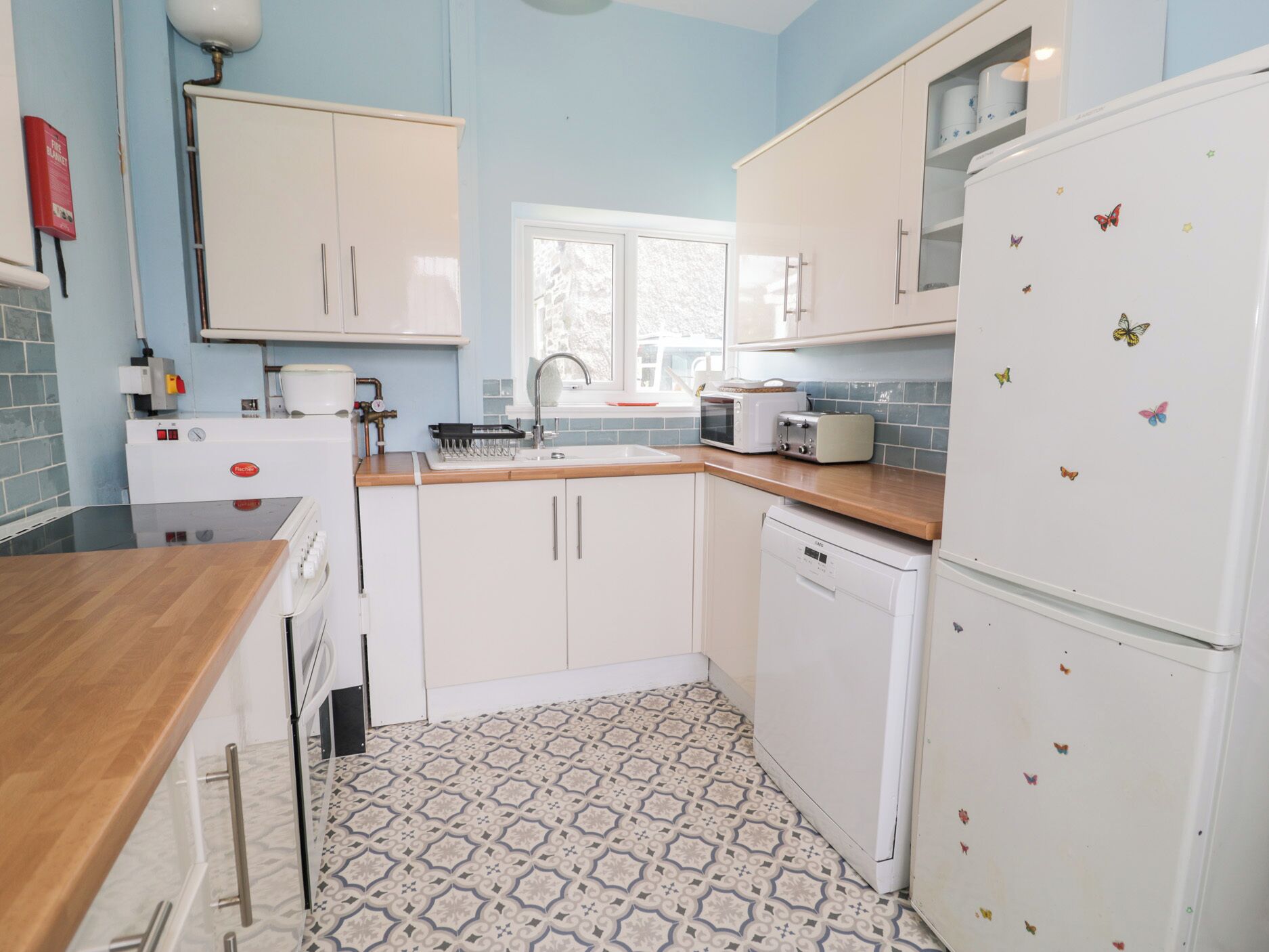 A compact kitchen with white cabinets, a microwave, a toaster, and a refrigerator with butterfly magnets.