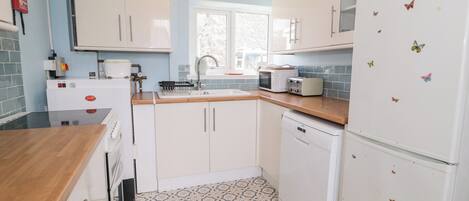 A compact kitchen with white cabinets, a microwave, a toaster, and a refrigerator with butterfly magnets.