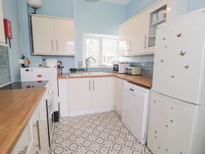 A compact kitchen with white cabinets, a microwave, a toaster, and a refrigerator.