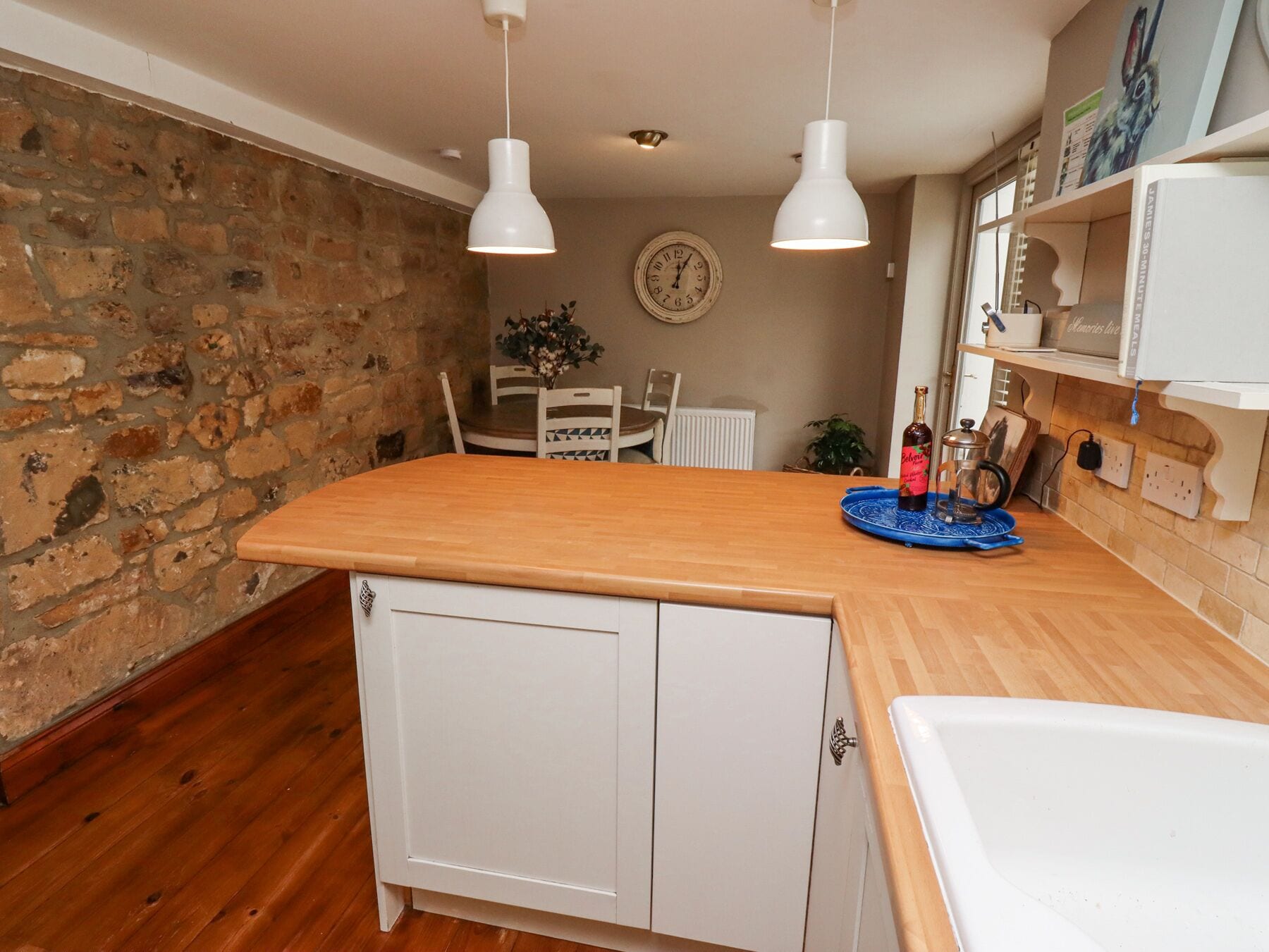 Una cocina con encimera de madera, armarios blancos e iluminación colgante.