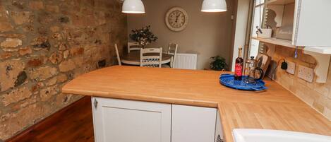 Una cocina con encimera de madera, armarios blancos e iluminación colgante.