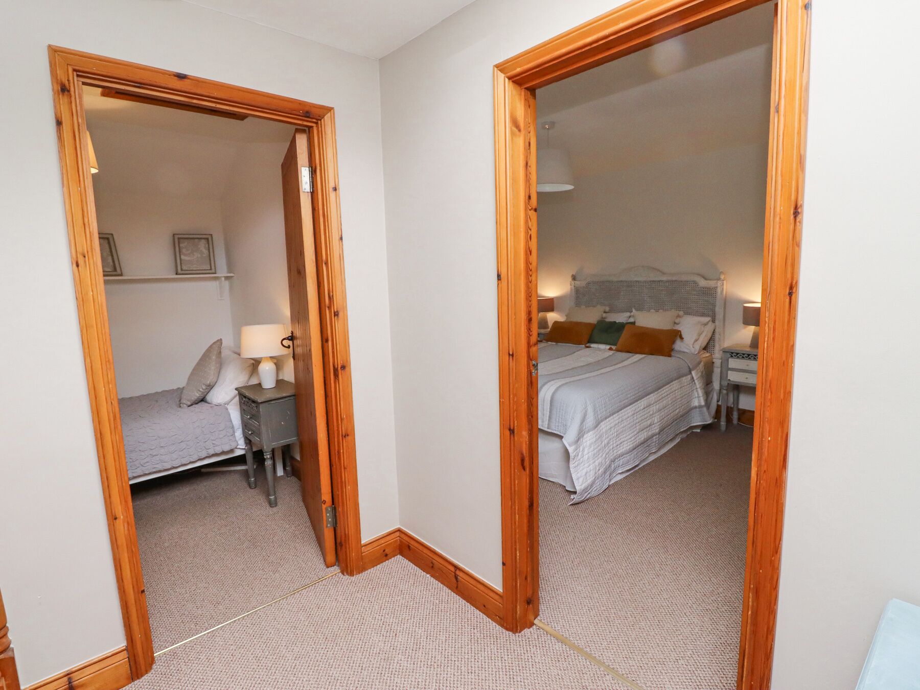 A bedroom with a bed, bedside table, lamp, and a mirror.