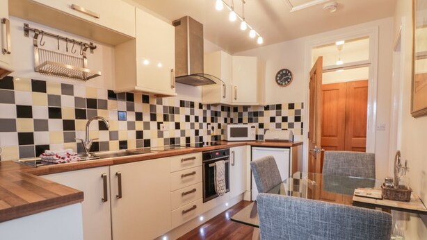 A modern kitchen with white cabinets, a microwave, a stove, and a checkered backsplash. - Station View (Pickering)