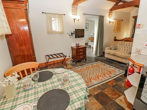 A dining area with a table set for four, a wooden chair, a bench, and a patterned rug.