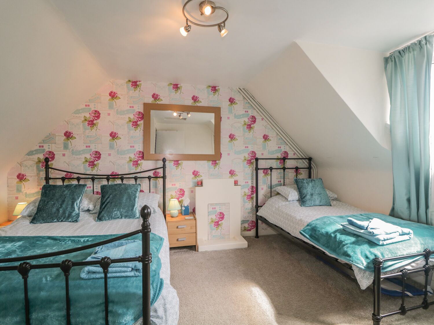 Une chambre avec deux lits, un miroir, une commode et un escalier.