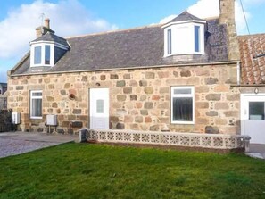 A stone house with a tiled roof, a small porch, and a door with a window above it. - Coastal Cottage (Fraserburgh)