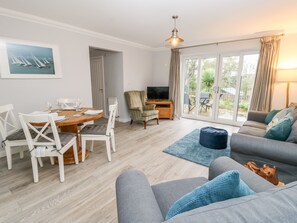 Relax in this stylish living room with a sofa, dining table, and TV.