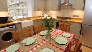 Una cocina con una mesa de comedor para cuatro personas, un microondas, una estufa y un lavaplatos.