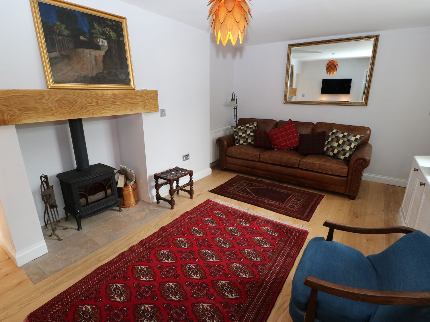Una sala de estar con chimenea, un sofá, una mesa de centro, un sillón azul y un tapete estampado.