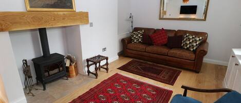 A living room with a fireplace, a sofa, a coffee table, a blue armchair, and a patterned rug.