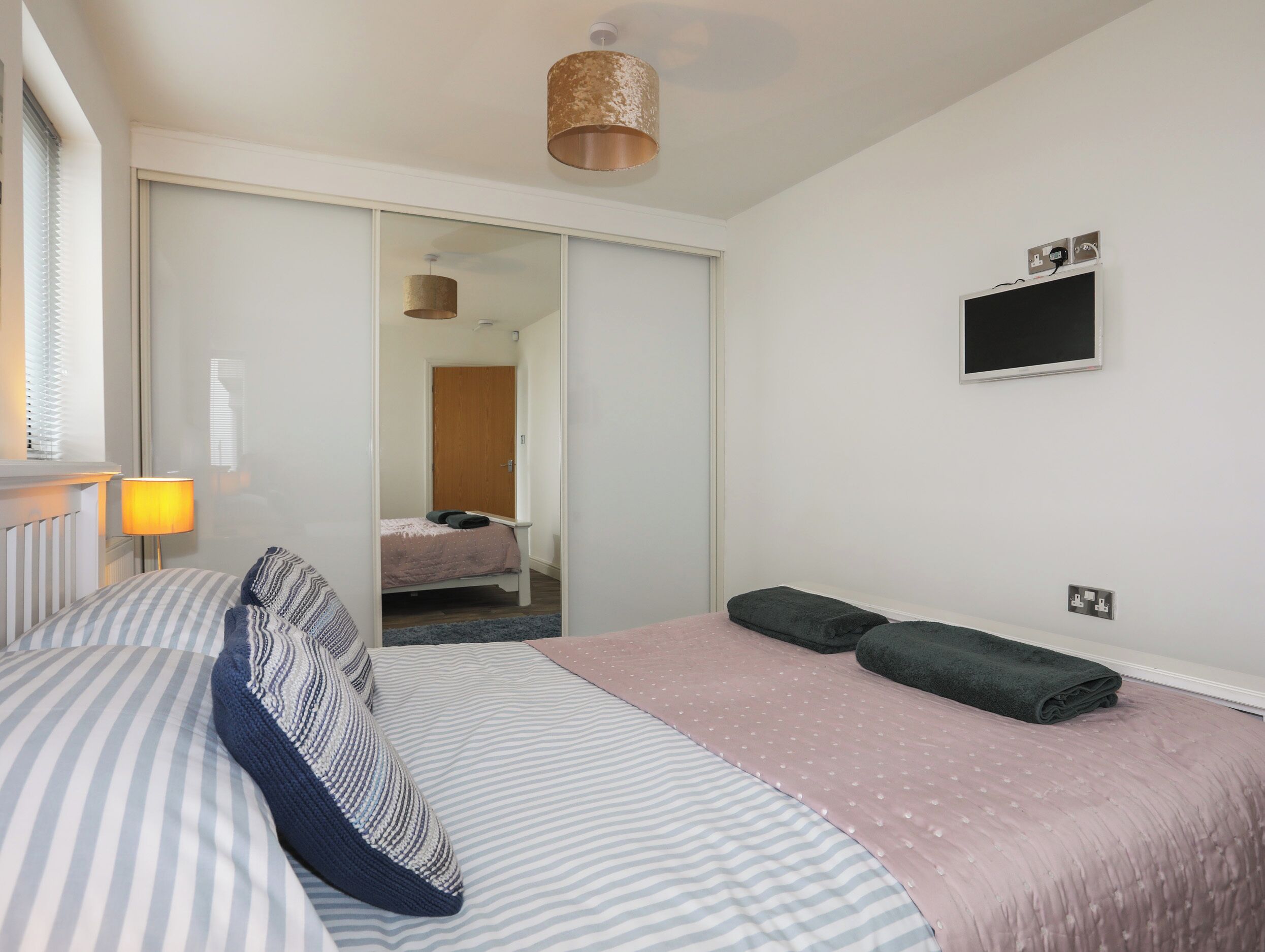 Habitación de hotel con cama, lámpara de noche, televisión de pantalla plana y armario.