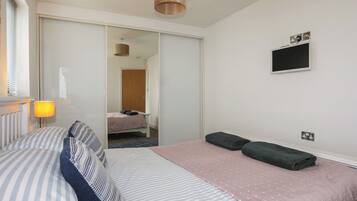 Habitación de hotel con cama, lámpara de noche, televisión de pantalla plana y armario.