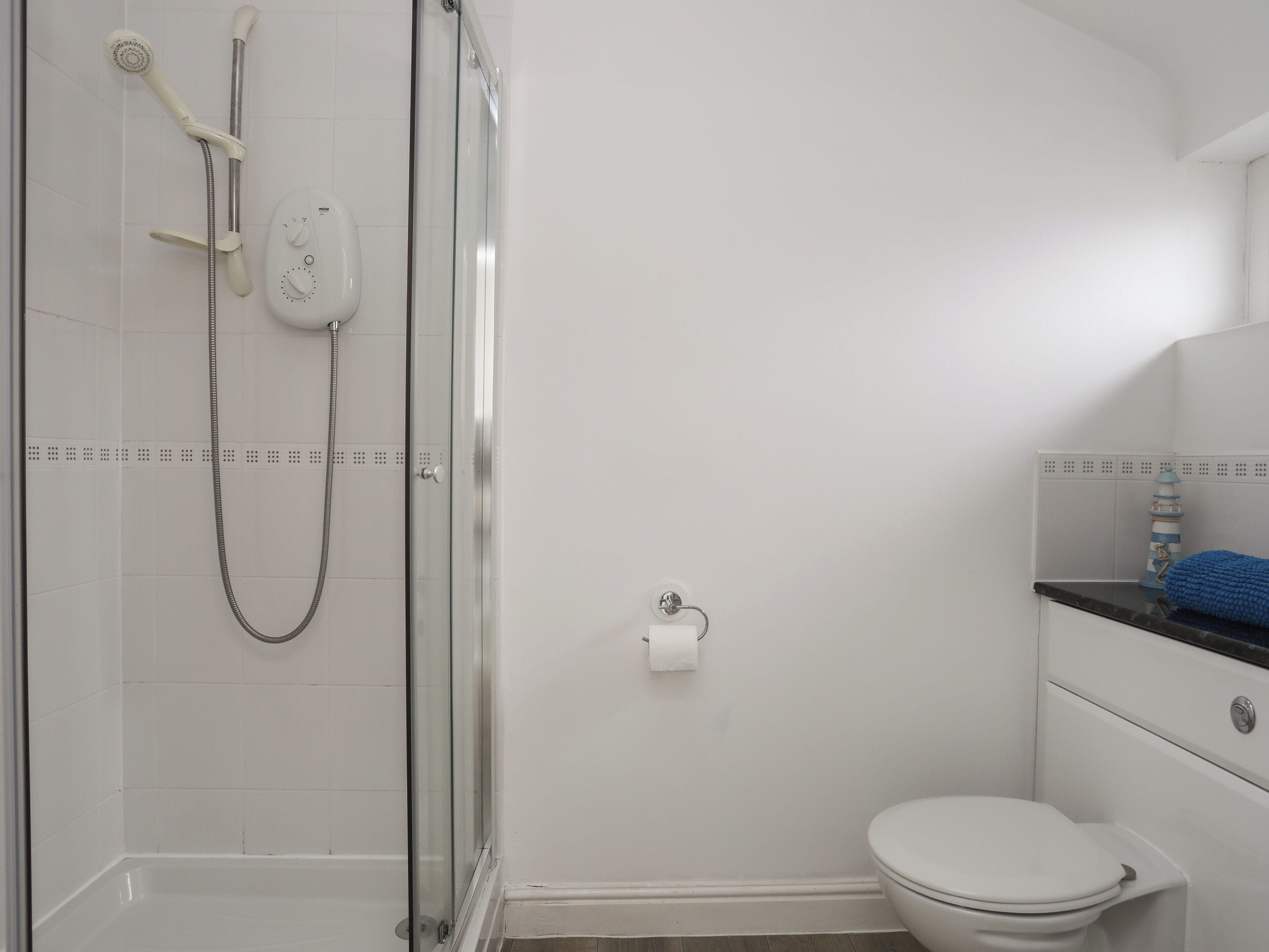 A bathroom with a glass-enclosed shower, a toilet, and a sink with a blue towel.