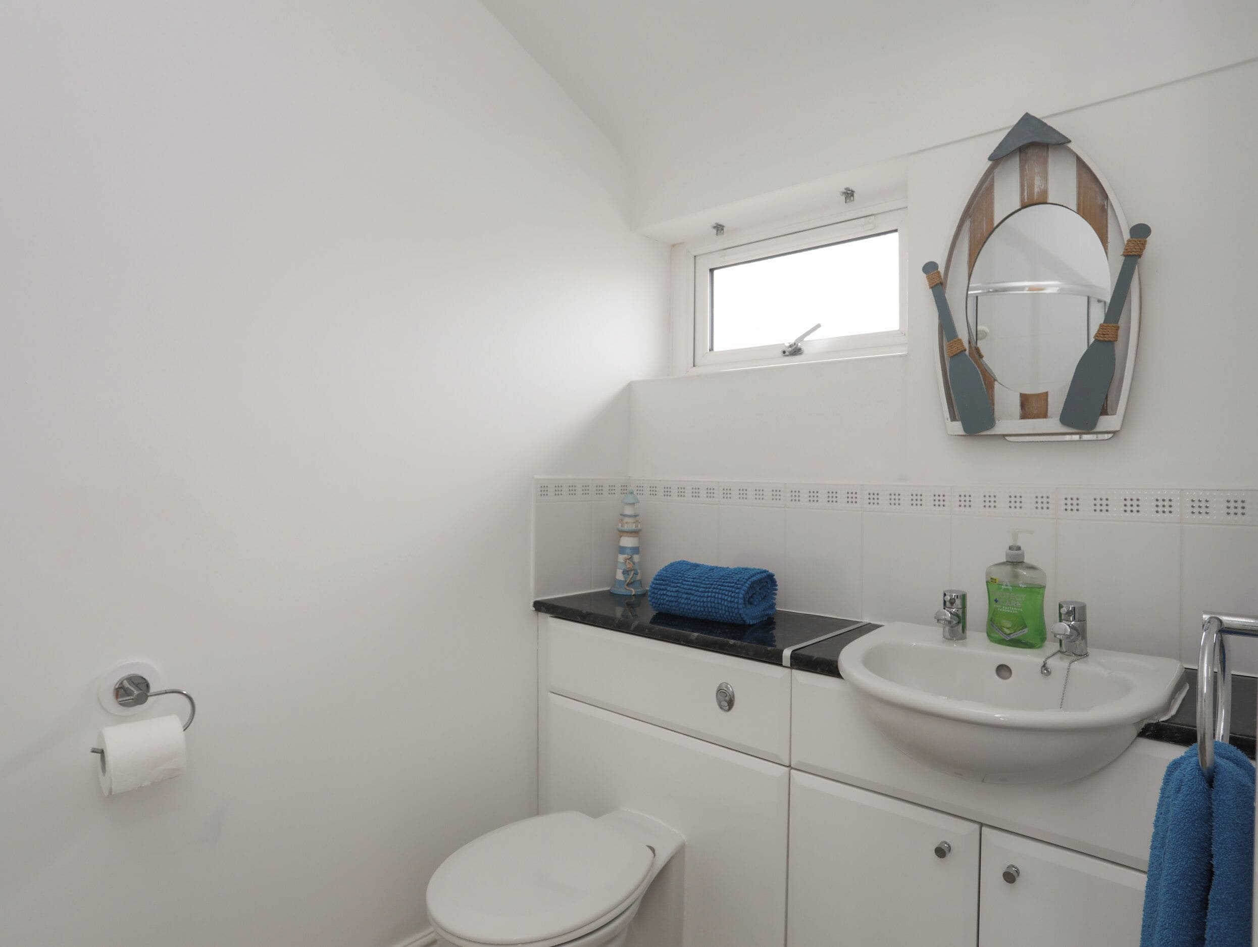 Un bagno piccolo e bianco con il water, un lavandino e uno specchio.