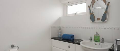 A small, white bathroom with a toilet, a sink, and a mirror.