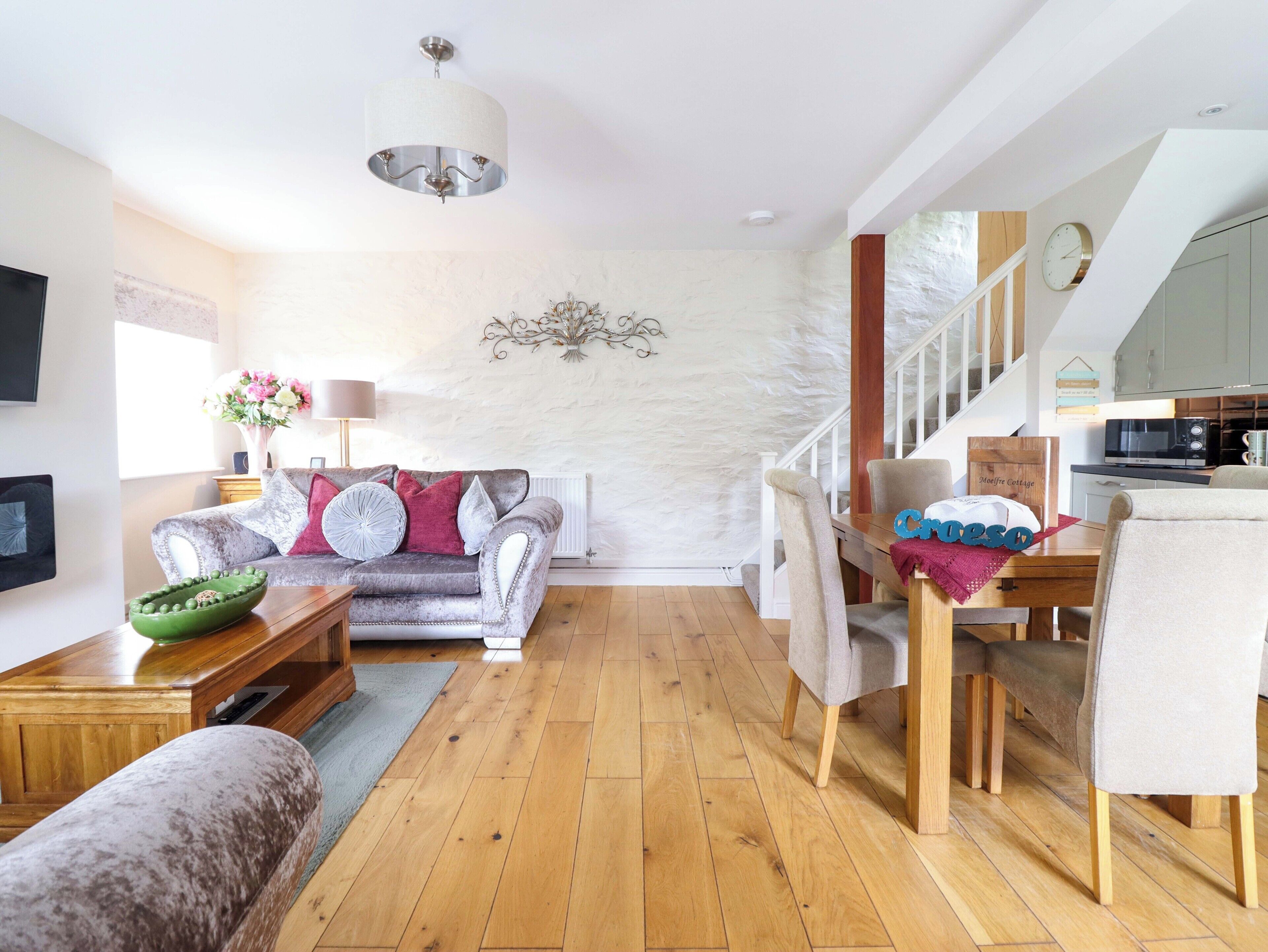 A modern living room with a sofa, dining table, and a staircase leading to a kitchen.