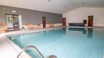 Relax by the pool with lounge chairs and a bench, surrounded by a serene atmosphere.