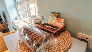A kitchen counter with a loaf of bread, a woven placemat, a jar of chocolate spread, and tea bags. - Field Cottage (Saltburn-by-the-Sea)