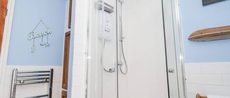 Una ducha con cerramiento de vidrio, cabezal de ducha de mano y panel de control en la pared.