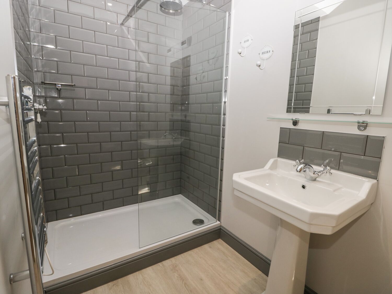A modern bathroom with a glass-enclosed shower, a white sink, and a mirror above it.