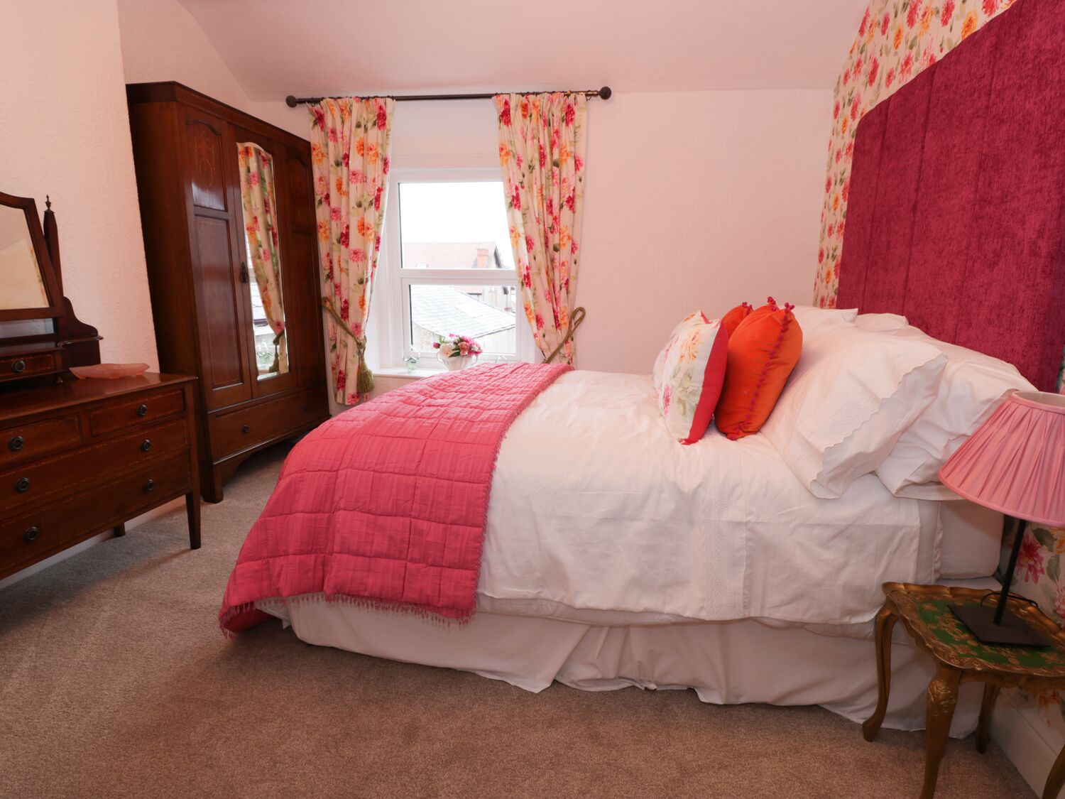 Un dormitorio con cama, cómoda, espejo y ventana con cortinas.
