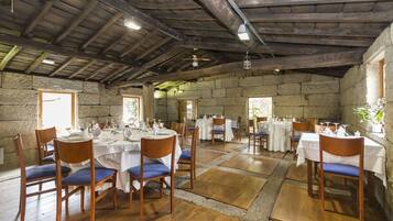 A restaurant with stone walls, wooden tables, and blue cushioned chairs.