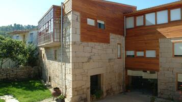 Une maison moderne à deux étages, dotée d’une façade en pierre et d’étages supérieurs en bois.