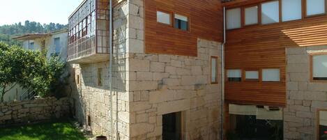 Una casa moderna de dos pisos con fachada de piedra y niveles superiores de madera.