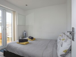 Un dormitorio con cama, un radiador, una ventana y una puerta que da a un espacio al aire libre.
