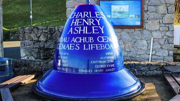 Un monumento azul con inscripciones, un muro de piedra y una placa en el fondo.