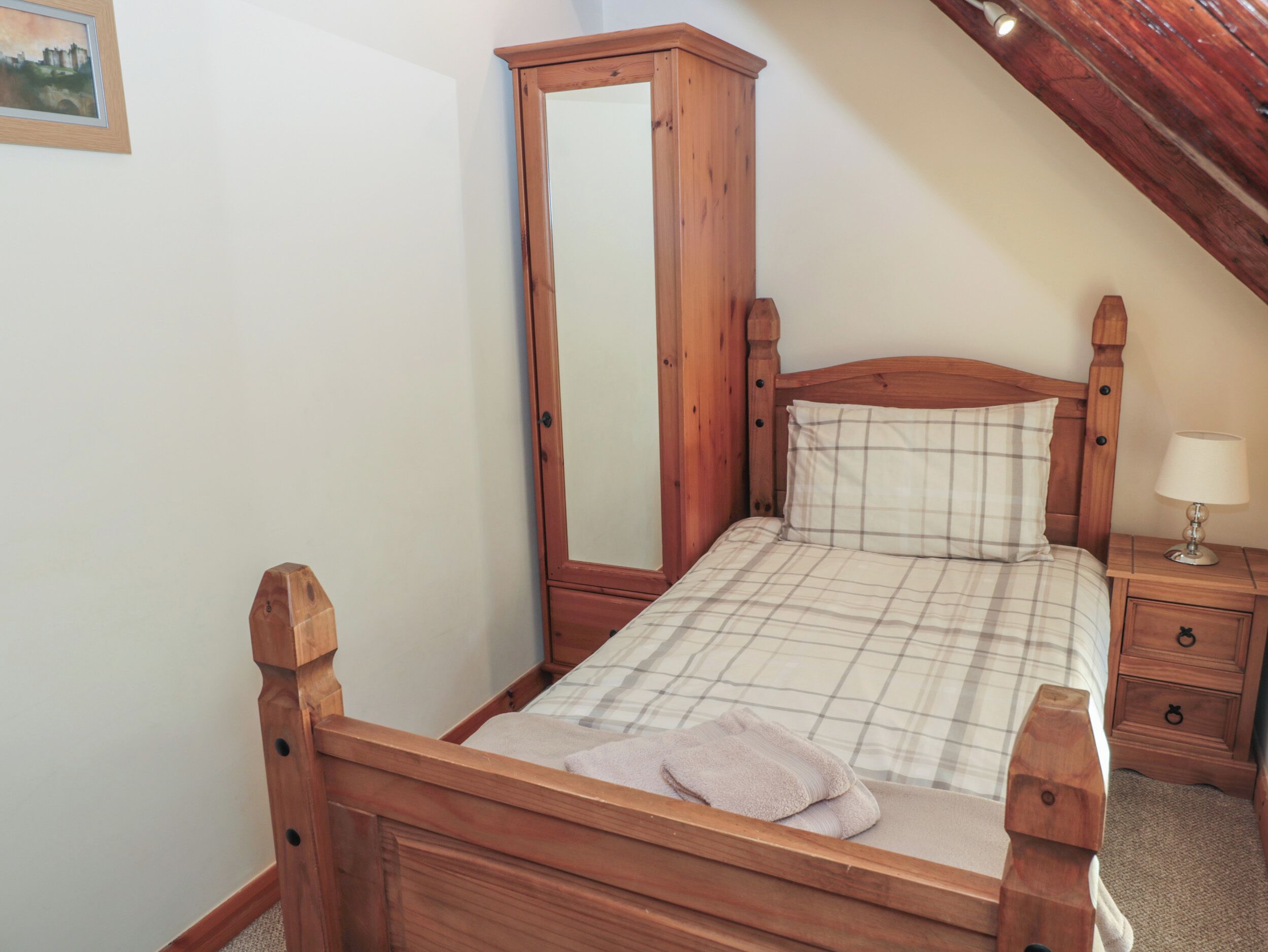 Una camera da letto con un letto in legno, un comodino con una lampada e un armadio.