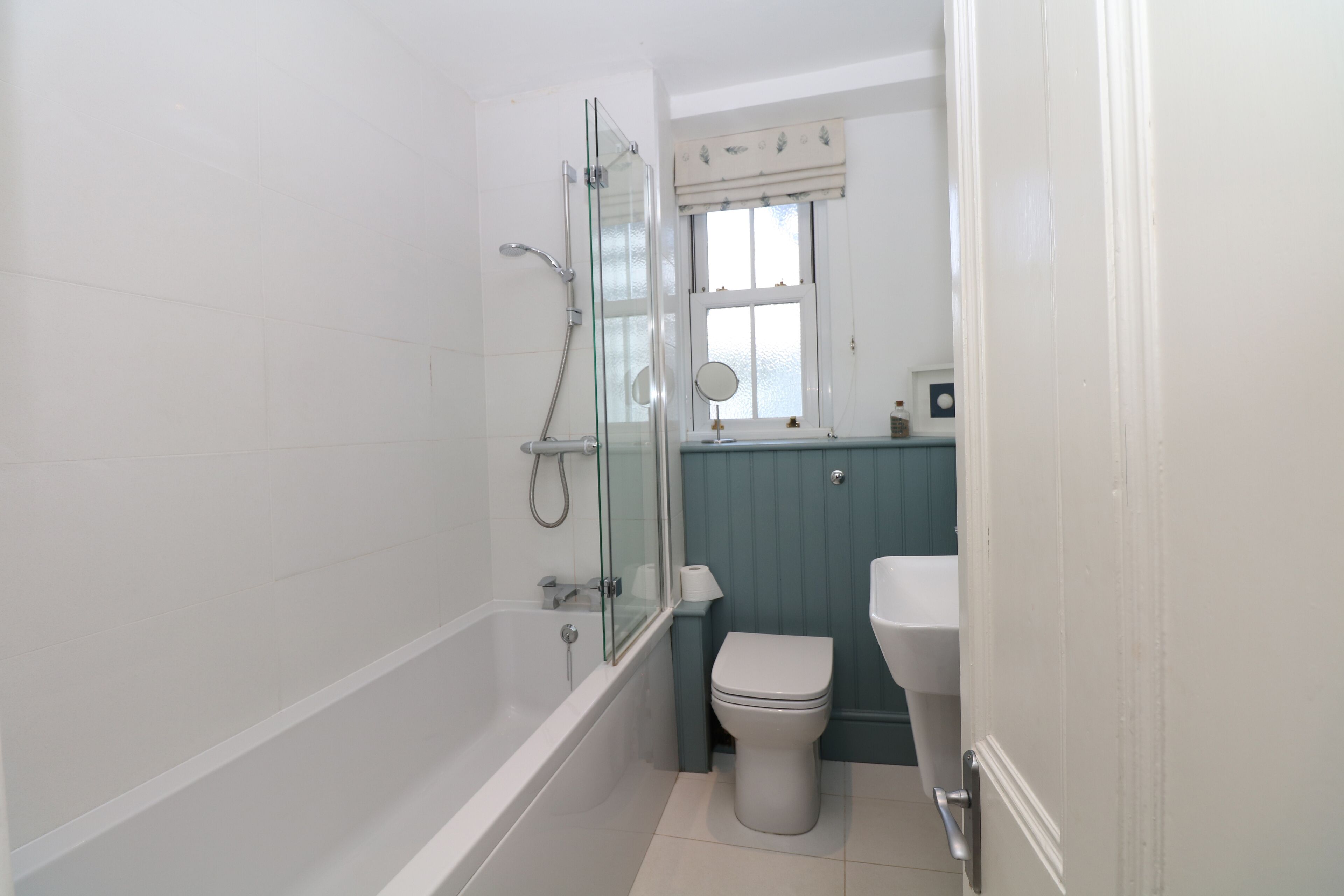 Une salle de bain avec une douche à parois de verre, des toilettes blanches et un lavabo.
