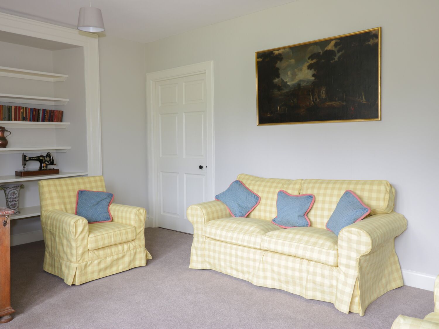 A room with a checkered sofa set, a bookshelf, and a door.