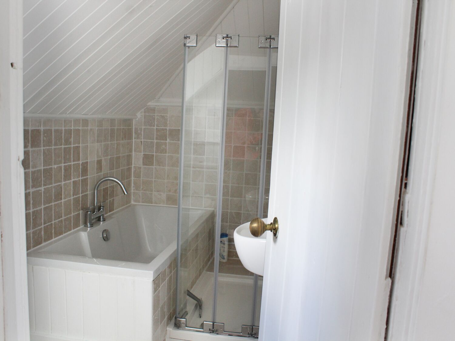 A bathroom with a bathtub, a shower enclosure, and a sink.