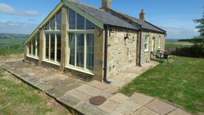 A stone house with a gabled roof and large windows.