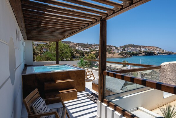 A rooftop terrace with a hot tub, wooden furniture, and a view of the coastline. - Nostos Beach Boutique Hotel (Mylopotamos)