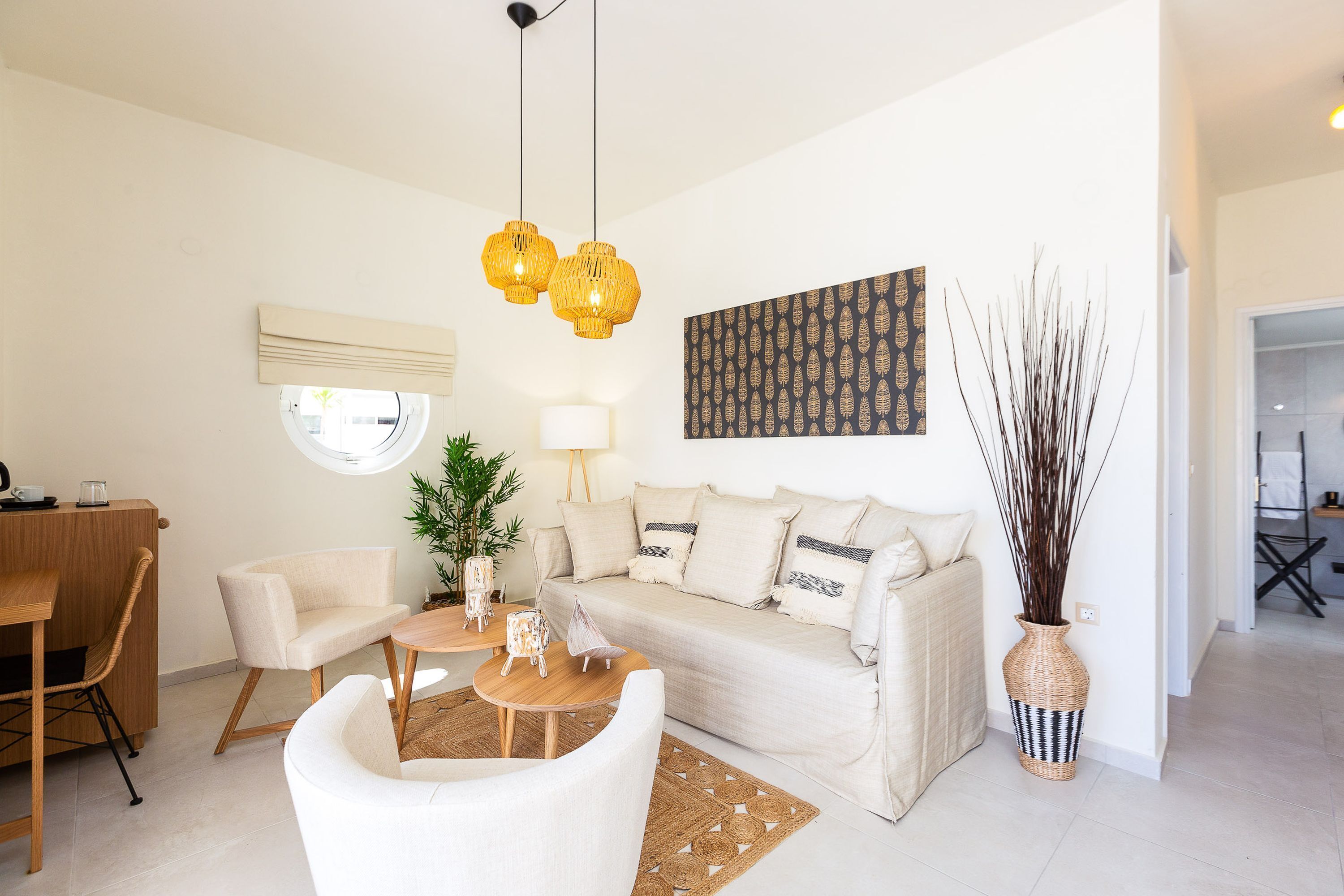 Una sala de estar moderna con un sofá, sillas, una mesita de centro y un jarrón decorativo.