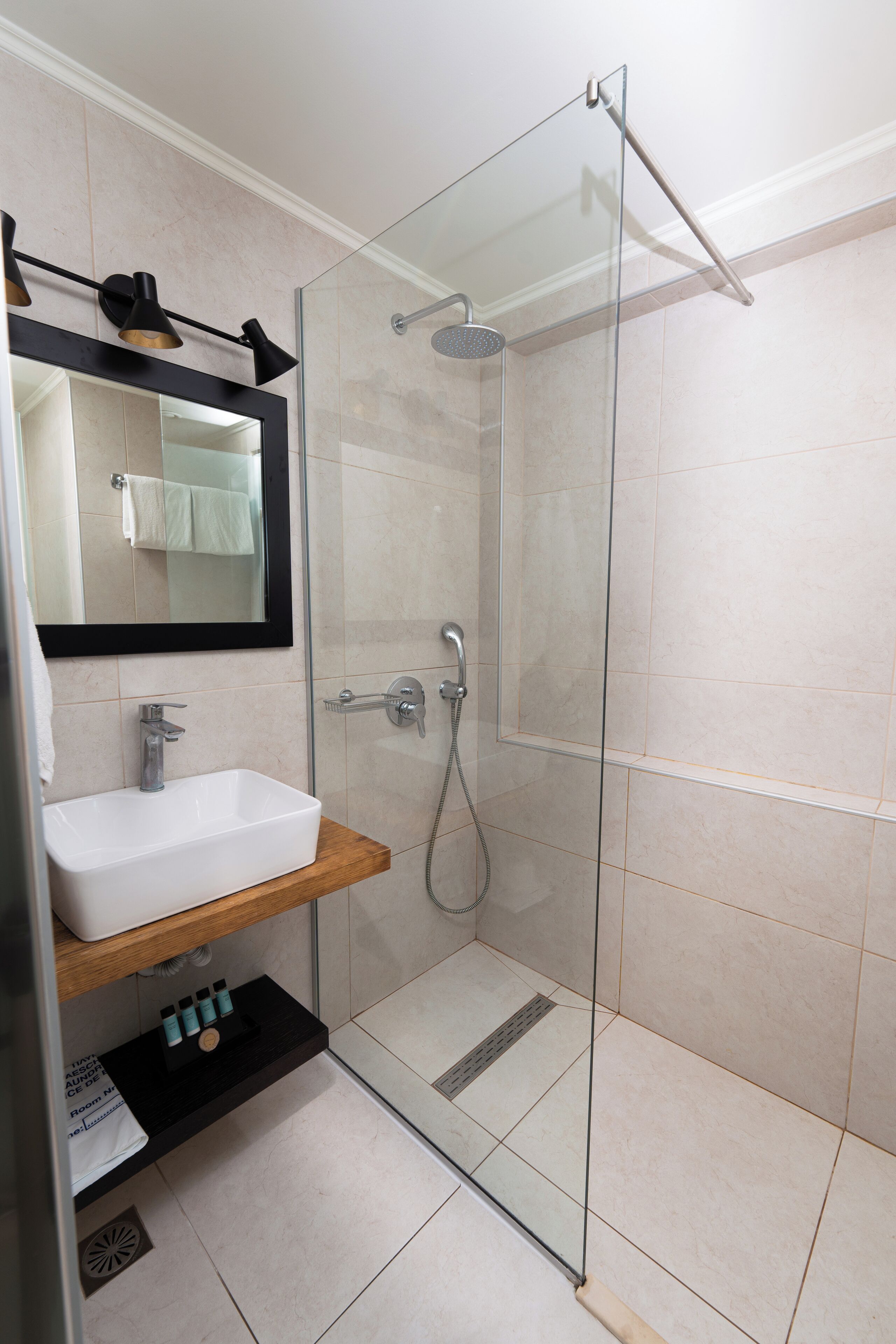 A modern bathroom with a glass-enclosed shower, a white sink, and a mirror above it.
