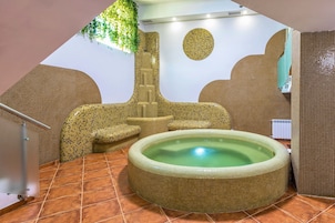 Zona de spa con bañera de hidromasaje, paredes enlosadas y una escalera.