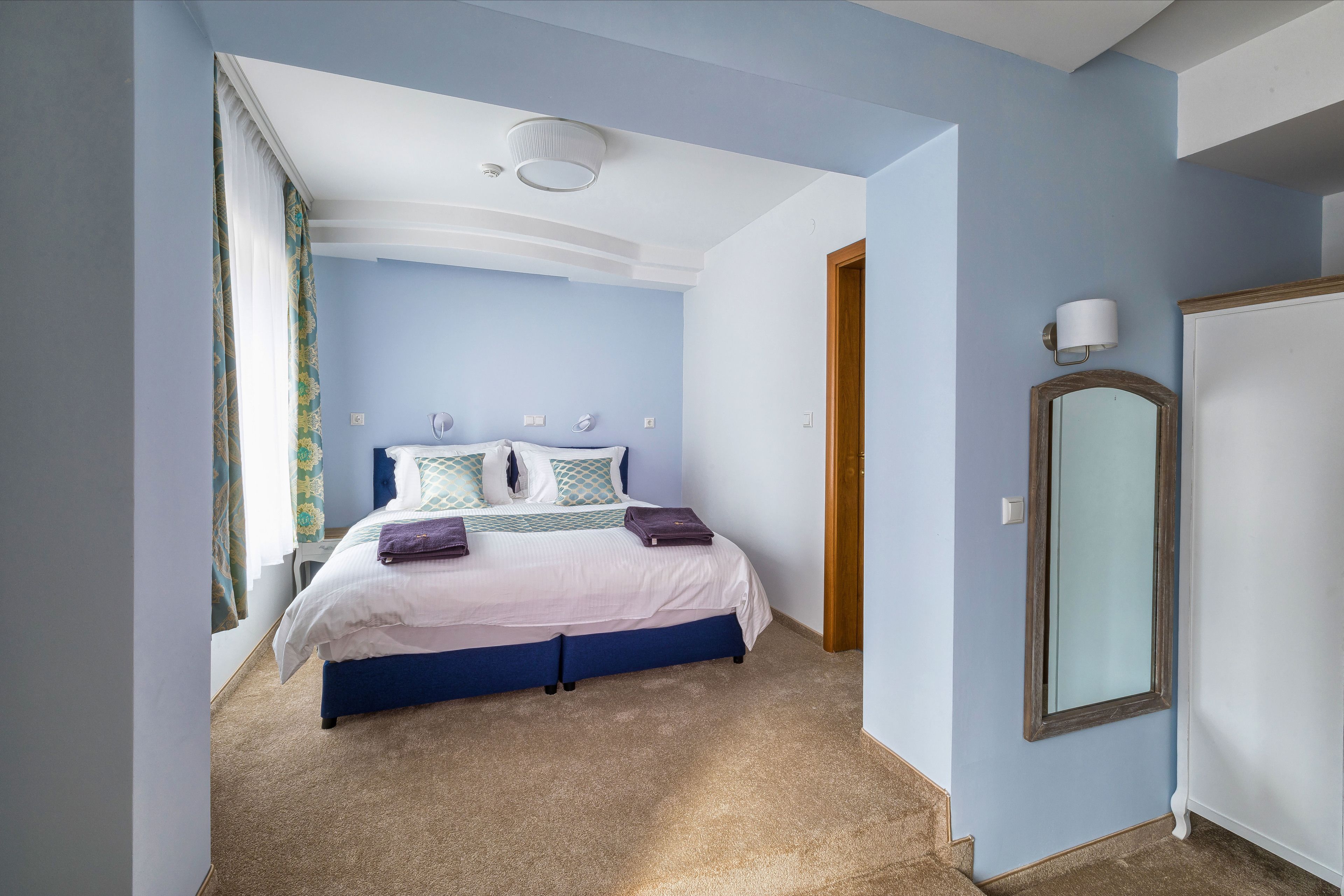 Una camera da letto con un letto, un comodino, uno specchio e una porta.