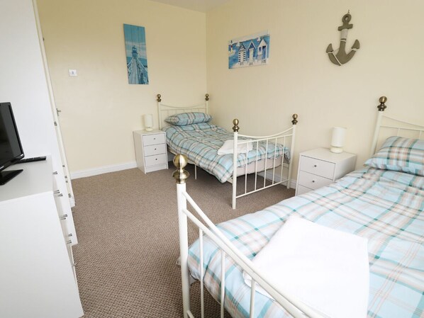 A bedroom with two single beds, a desk, a chair, a TV, and a wardrobe. - Anneddle (Holyhead)