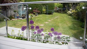 Ein Garten mit Glasgeländer, einer Rasenfläche und unterschiedlichen Pflanzen.