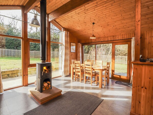 Ein Holzinnenraum mit Kamin, großen Fenstern und einem Essbereich.