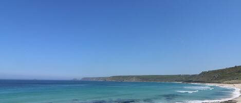 Una platja amb aigua turquesa cristal·lina, sorra daurada i roques emergents.