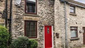 A stone building with a red door, a satellite dish, and a small window. - Mill Bridge Cottage (Hope Valley)
