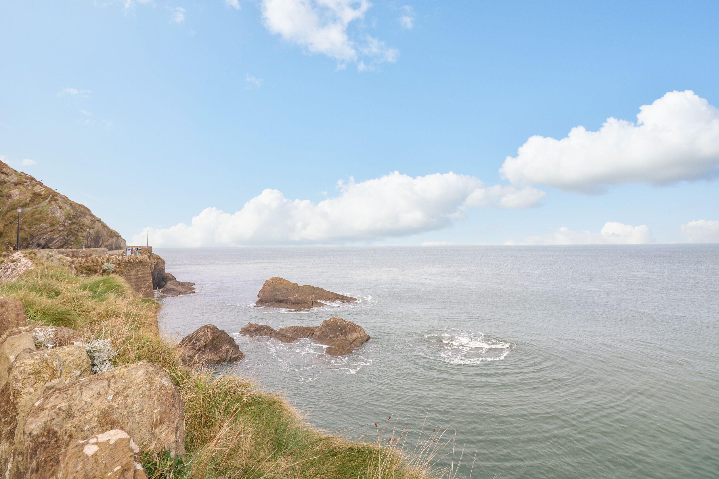 A coastal landscape with rocky cliffs and calm sea.