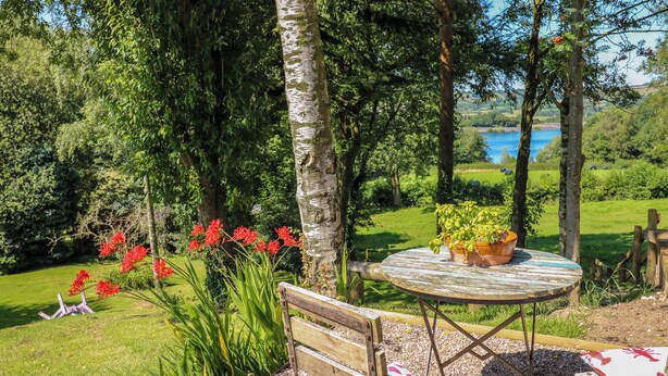 Un banco de madera y una mesa en un jardín con vistas a un lago.