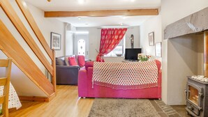 A cozy living room with a staircase, a fireplace, and a sofa. - 40 New Row (Pwllheli)