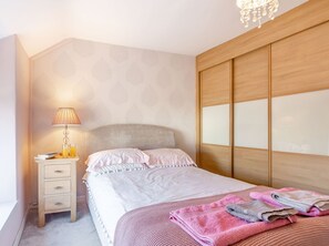 A neatly arranged bedroom with a bed, bedside table, lamp, and a wardrobe. - 40 New Row (Pwllheli)